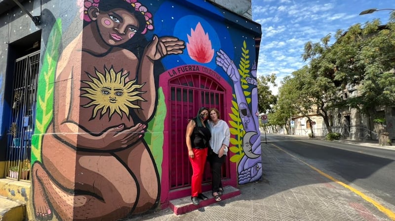 Giovanna Grandón and Jane Suiter (right) in front of one of many political murals that proliferate in Santiago.