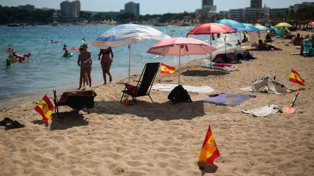 Spanish flags being used as social distancing markers stick out from the sand in Palma, Mallorca,  one  of the popular Balearic Islands in Spain. Photograph: Joan Mateu/AP