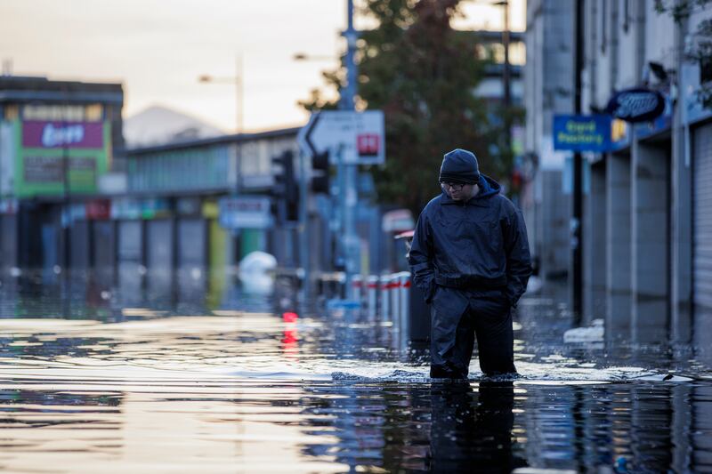 Michael McShane walks through flood water on Market Street in Downpatrick, Northern Ireland. Photograph: Gareth Fuller/PA