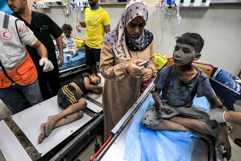 A woman uses a phone while waiting with two children at a trauma ward at Nasser hospital. Photograph: Mahmud Hams/AFP via Getty Images