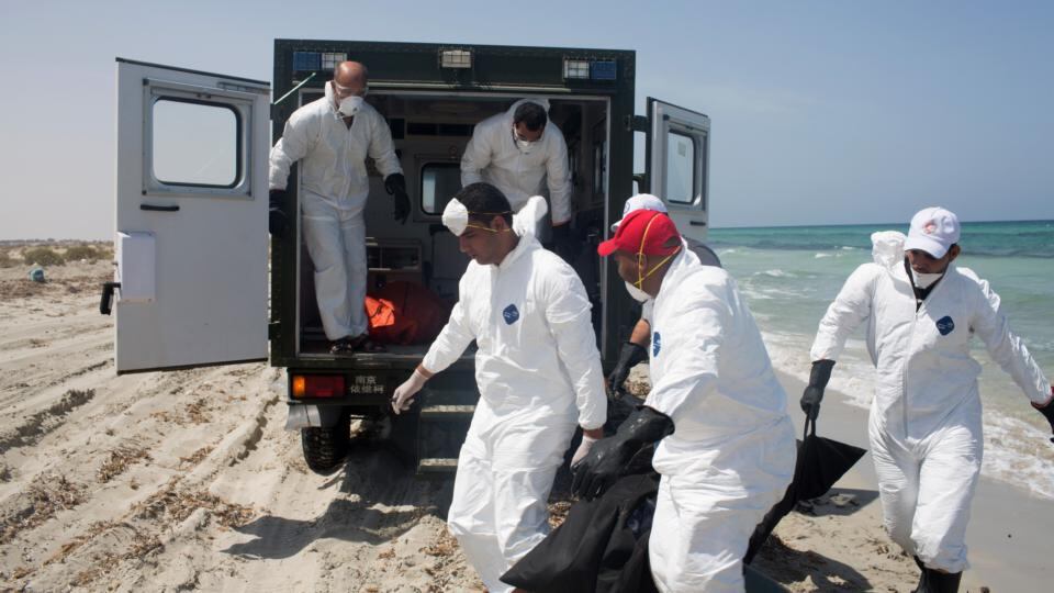 Workers for the Red Crescent carry the body of a dead migrant at Zuwara, about 105 kilometers west of Tripoli, Libya, on Friday. Two ships sank on Thursday off the western Libyan city, and over 100 bodies have been recovered. Photograph: AP