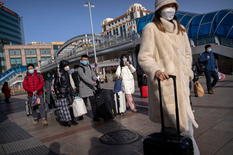 Travellers wearing face masks walk toward the entrance of Beijing Railway Station. Photograph: Mark Schiefelbein/AP