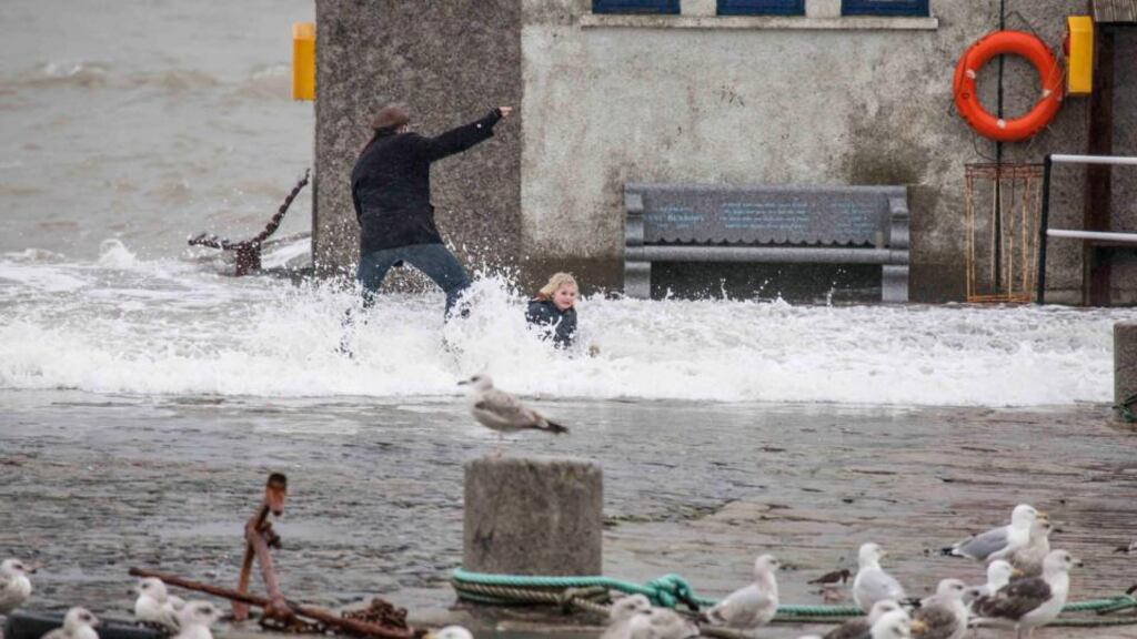 A man and a child feel the force of a wave on the pier at Bullock Harbour, Co Dublin, yesterday.   Photograph: Aidan Tarbett/Provision