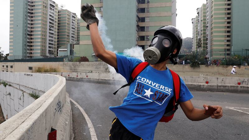 A who is prepared for tear gas throws back a canister during the demonstration in Caracas. Photograph: Reuters