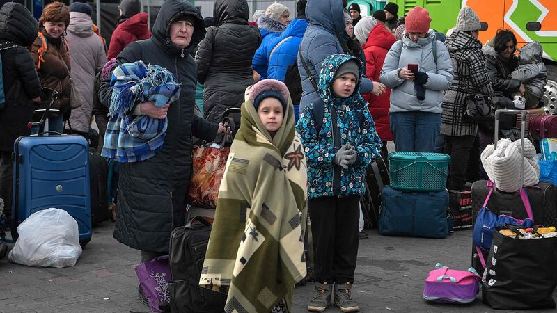 People stand with their luggage as they wait to board buses transporting them further into Poland or abroad from the temporary shelter for refugees located in a former shopping centre between the Ukrainian border and the Polish city of Przemysl. Photograph: Louisa Gouliamaki/AFP via Getty Images