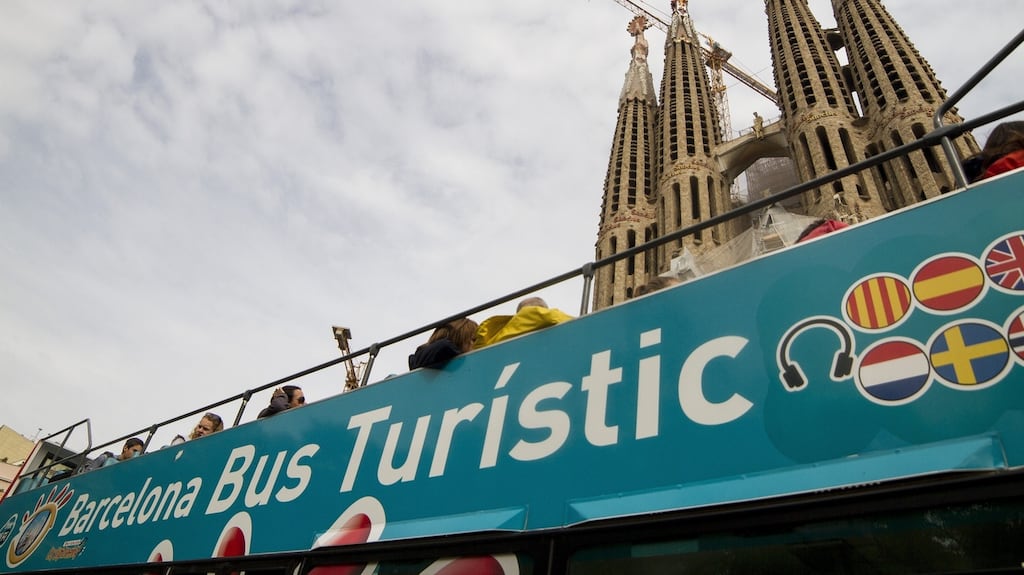 A tourist bus pass by the basilica of the Sagrada Familia by Antoni Gaudi in Barcelona, where the city council is clamping down on illegal lettings blamed for driving up rents. Photograph: Albert Llop /Anadolu Agency/Getty Images