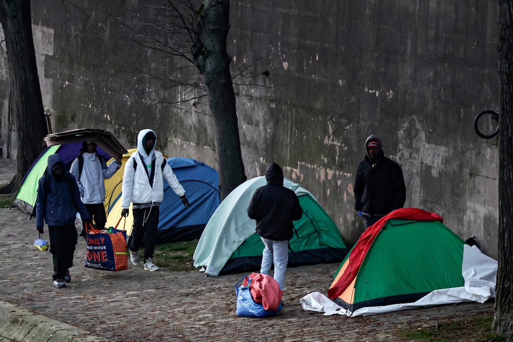 Migrants expelled from the Gâité Lyrique theare in Paris carry belongings as they walk by tents along Seine on Friday. Photograph: Stephane de Sakutin/Getty