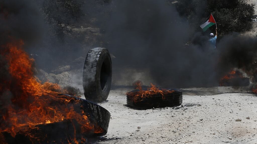 A Palestinian protester waves Palestine flag during clashes with Israeli troops after a protest against Israeli settlements at Beta village near the West Bank City of Nablus. Photograph: Alaa Badarneh/EPA.