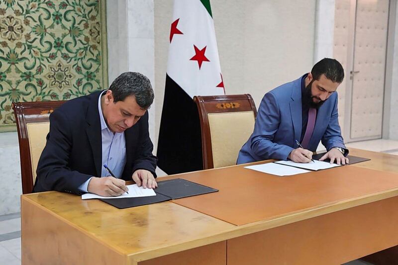 Syria’s interim president Ahmed al-Sharaa and Mazloum Abdi, commander of the US-backed, Kurdish-led Syrian Democratic Forces, sign an accord in Damascus. Photrograph: Sana via AP