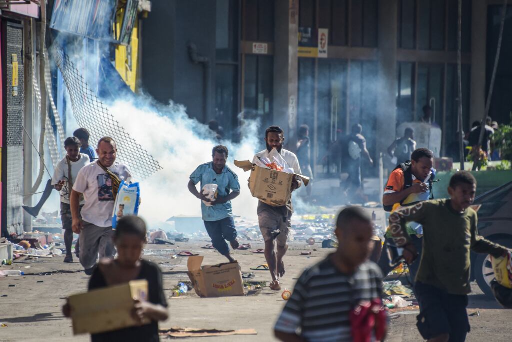 Crowds leave shops with looted goods amid a state of unrest in Port Moresby, Papua New Guinea, on Wednesday. Photograph: Getty Images