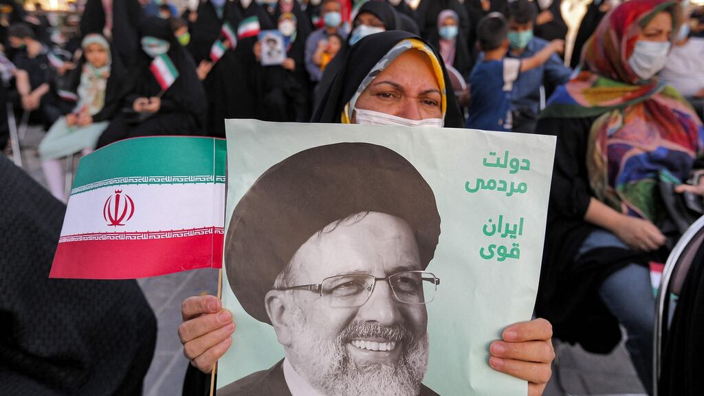 A woman holds a poster of Iran’s newly elected president Ebrahim Raisi, with text in Persian reading ‘government of the people, strong Iran’, as supporters celebrate his victory in Imam Hussein square in the capital Tehran on Saturday. Photograph: Atta Kenare /AFP via Getty Images
