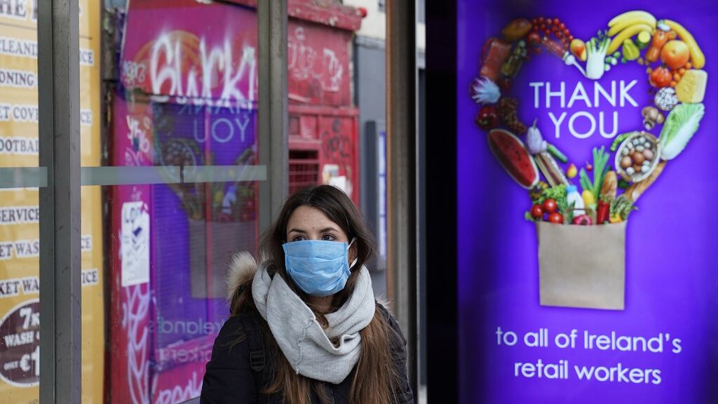A woman wearing a mask at a bus stop in Dublin which displays a message “Thank you to all of Ireland’s retail workers.” Photograph: Reuters/Clodagh Kilcoyne