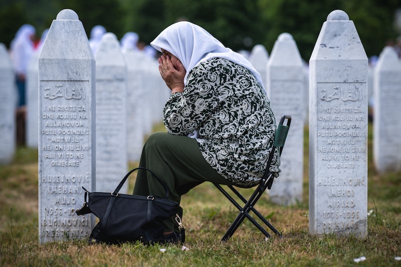 A woman reacts as she sits among gravestones at the memorial cemetery in the village of Potocari on the 30th anniversary of the Srebrenica massacre. Photograph: Andrej Isakovic/AFP