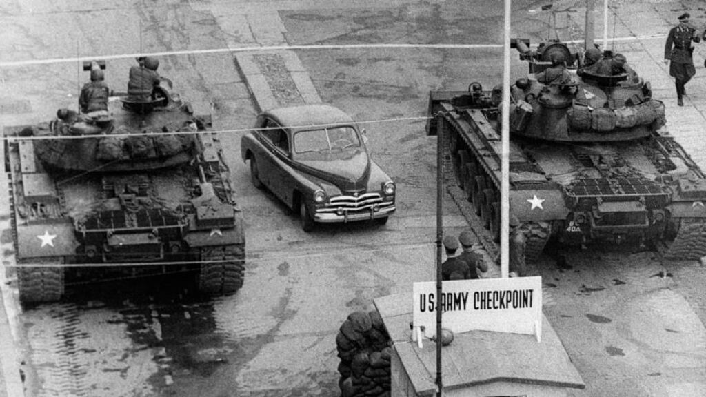 An armoured water truck cleans the street of debris after the East German government ordered construction work to strengthen the border crossing at Heinrich-Heine- Strasse (aka Checkpoint Delta) on the Berlin Wall, December 4th, 1961 A car drives between US tanks, in October 1961, across the famous borderof the US sector in Berlin, at Checkpoint Charlie crossing point which was used by diplomats and foreigners