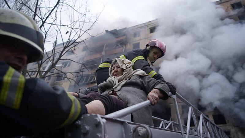 Firemen help an elderly woman to evacuate from an apartment building hit by shelling in the Obolon district of Kyiv. Photograph: State Emergency Service of Ukraine/AFP via Getty Images