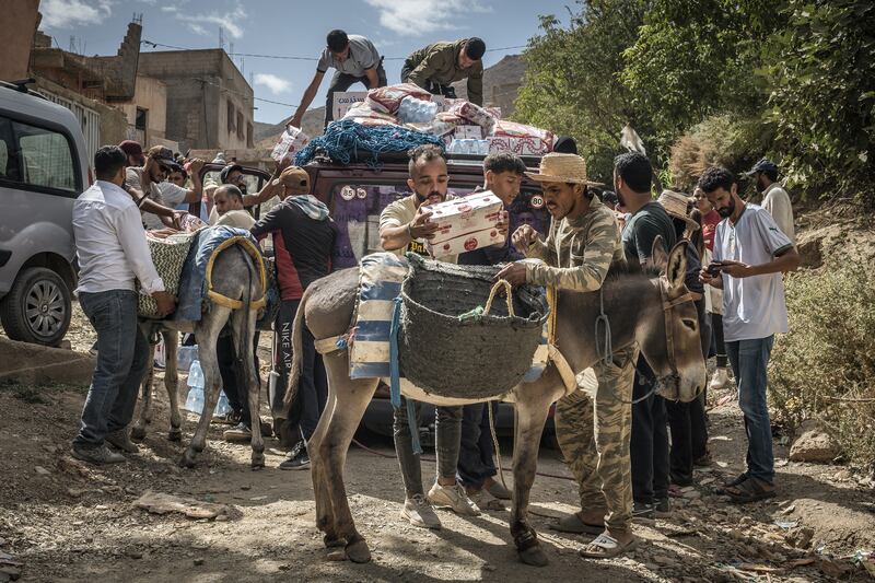People load aid on to donkeys to transport it to Douar Tnirt village in the hard-hit Al Haouz province in Morocco. Photograph: Sergey Ponomarev/New York Times