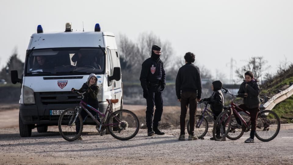 On guard: a policeman talks to migrant children in the “Jungle” camp. Photograph: Carl Court/Getty