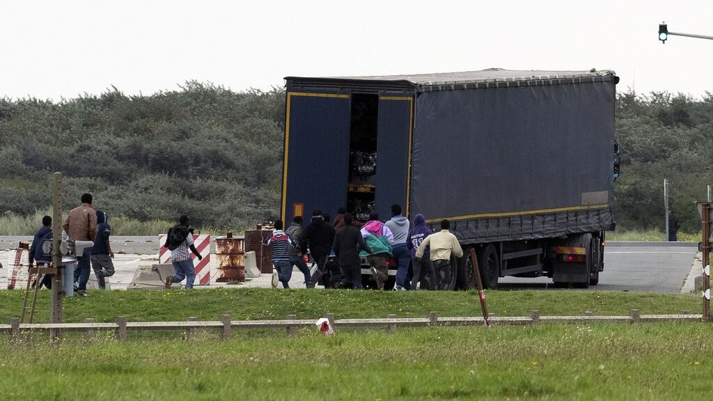 Illegal migrants run towards a truck about to board a ferry to England. Photograph:  Denis Charlet/AFP via Getty Images