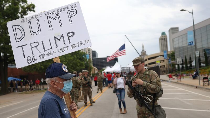 Veteran Richard Saul carries a sign that reads “Dump Trump” as a member of the Oklahoma National Guard stands nearby ahead of a Donald Trump election campaign rally at the BOK Center, in Tulsa, Oklahoma. Photograph: Win McNamee/Getty Images