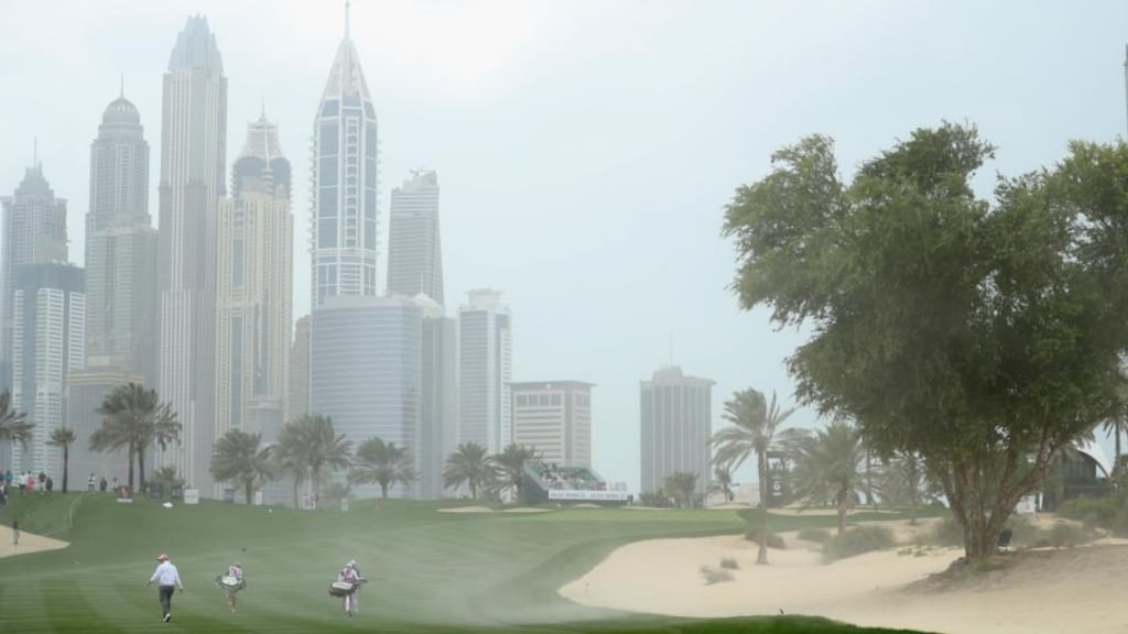 Players walk up the eighth fairway as strong wind blows sand across the hole during the second round of the Omega Dubai Desert Classic. Photograph: Little/Getty Images