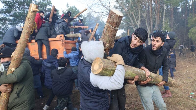 Migrants carry firewood as they gather at the Belarus-Poland border near Grodno, Belarus. Photograph: Ramil Nasibulin/ BelTA via AP