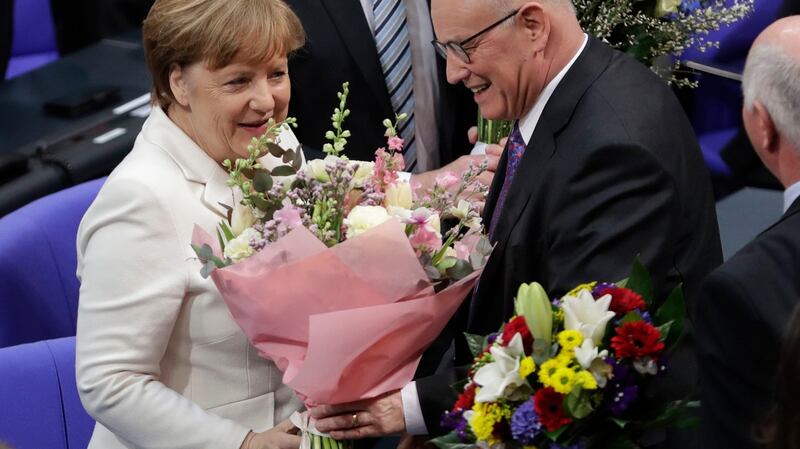 German Chancellor Angela Merkel receives flowers from the  Christian Democratic parliamentary group leader Volker Kauder after she was elected for a fourth term  in Berlin. Photograph: Michael Sohn/AP