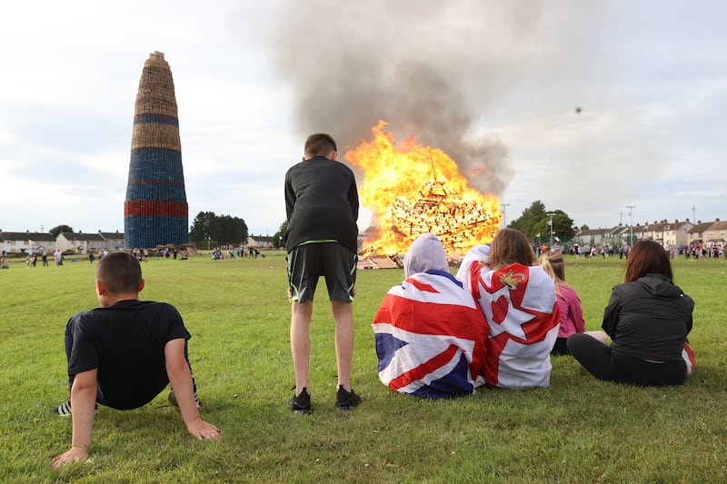 People gather at the Craigyhill bonfire in Larne, prior to it being lit on the Eleventh Night to usher in the Twelfth commemorations. Photograph: Liam McBurney/PA
