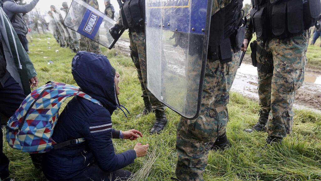 A Moroccan migrant kneels in front of Macedonian police officers as he tries to cross the Greek-Macedonian border near the Greek village of Idomeni. Photograph: Yannis Behrakis/Reuters