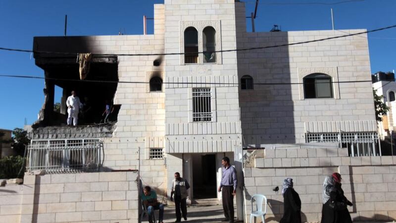 Palestinians at the partially burned home of one of the suspects in the kidnapping and murder of three Israeli teenagers, after the Israeli army set fire to the building in the West Bank village of Halhoul, near Hebron, today. Photograph: EPA