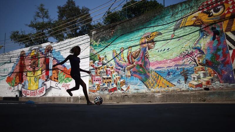 A girl plays soccer in front of graffiti created by acclaimed local graffiti artist Acme in the pacified Pavao-Pavaozinho community in Rio de Janeiro, Brazil. Photograph: Mario Tama/Getty