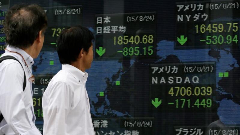 Businessmen watching closing information of Tokyo’s Nikkei Stock Average (L), New York Dow (R) and NASDAQ (bottom) in Tokyo, Japan, today. Photo: EPA