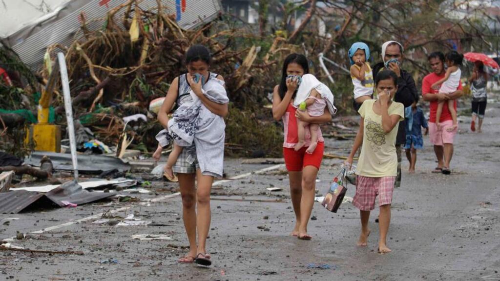 Residents cover their noses from the smell of decomposing bodies in Tacloban city in Leyte province in central Philippines yesterday. The city remains littered with debris from damaged homes as many complain of shortage of food, water and no electricity since typhoon Haiyan hit the province. Photograph: AP Photo/Bullit Marquez