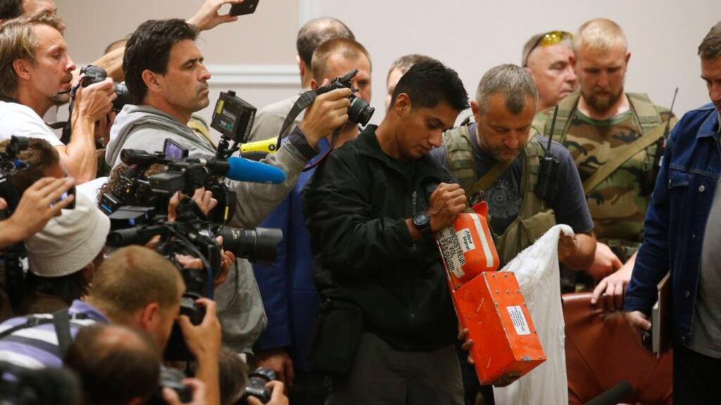 A Malaysian expert (C) examines a black box belonging to Malaysia Airlines flight MH17 during its handover from pro-Russian separatists, in Donetsk.