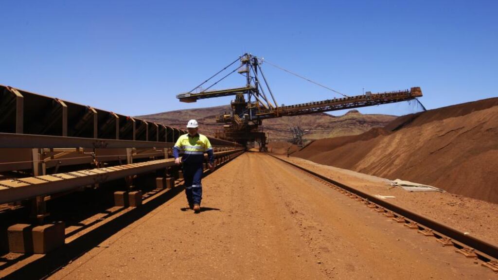 An employee walks past a stacker as it loads crushed iron ore at a processing facility in the Solomon mining hub in Western Australia. The mining industry, along with mining-related activities, accounts for almost 20 per cent of Australian GDP, and 10 per cent of employment. Photograph: Sergio Dionisio/Bloomberg