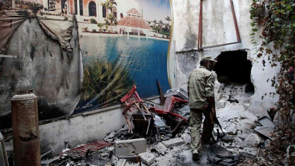 A Free Syrian Army fighter walks past a torn poster amid the rubble in the old city of Aleppo. REUTERS/Muzaffar Salman/Files