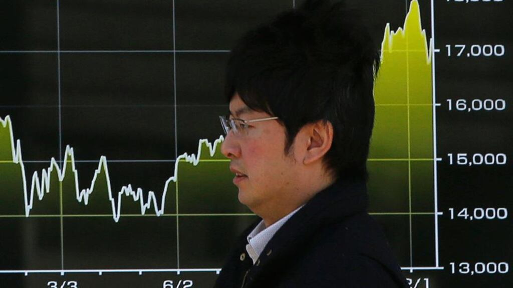 A man walks past an electronic graph showing recent Japan’s Nikkei stock average. Photograph: Issei Kato/Reuters