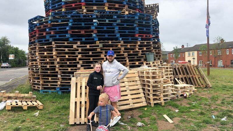 Miley Smith (11), Stephen Hunter and Jax Hunter (3) at the bonfire pyre at Tamar Street in east Belfast. Photograph: Peter Murtagh