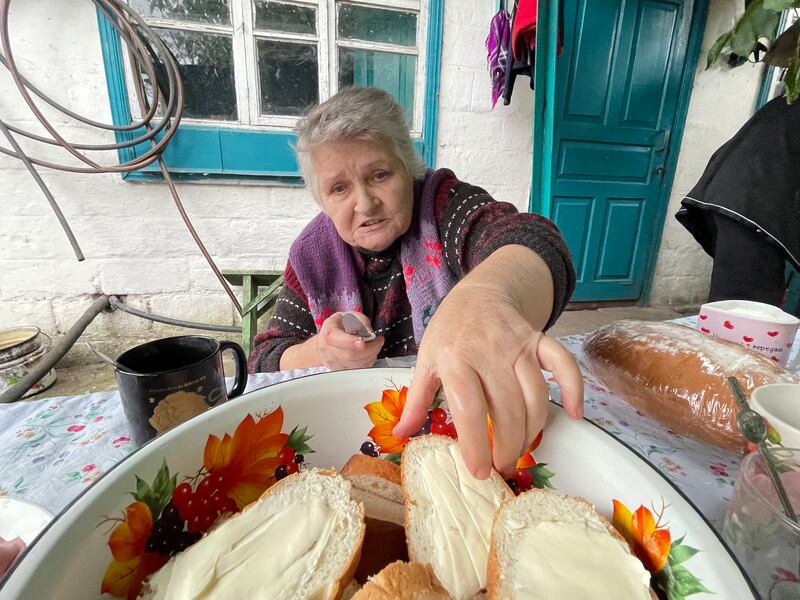 Klavdiya Pivovar butters bread in the yard of her cottage in Mospanove, northeastern Ukraine. Photograph: Daniel McLaughlin