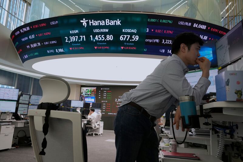 A currency trader watches monitors near a screen showing the Korea Composite Stock Price Index.