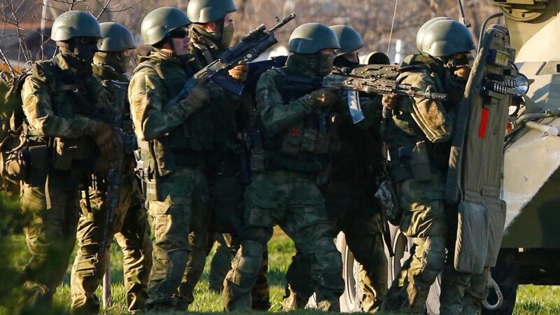 Armed men, believed to be Russian servicemen, take cover behind an armoured vehicle as they attempt to take over a military airbase in the Crimean town of Belbek near Sevastopol yesterday. Photograph: Shamil Zhumatov/Reuters