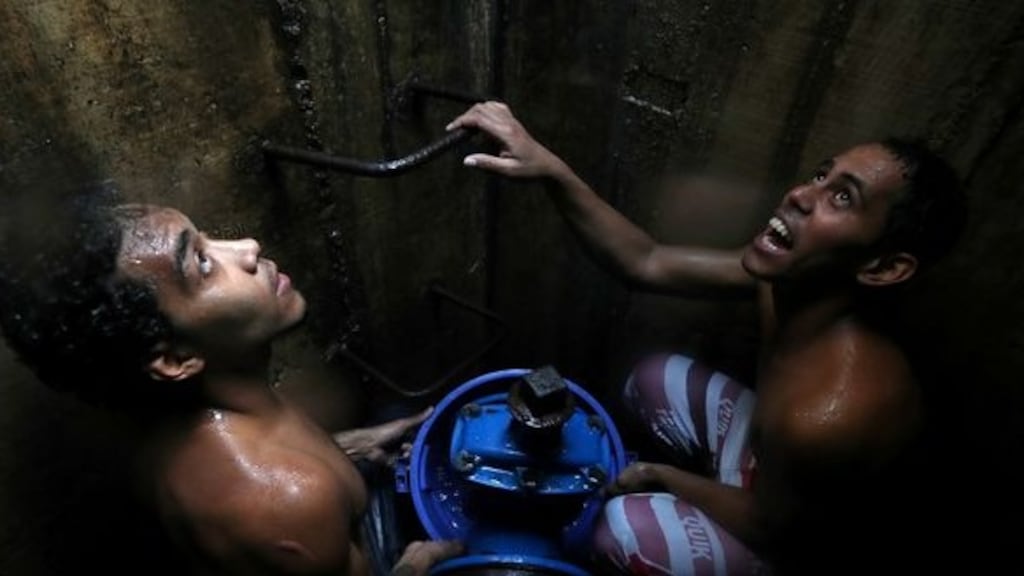 Locals collect water from an underground water main pipeline in Caracas, Venezuela. Photograph: Ivan Alvarado/Reuters