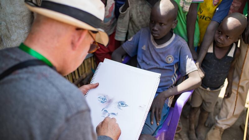 Brian Maguire sketches a young boy in the PoC camp in  Bentiu, South Sudan. Photograph: Steve De Neef/Concern Worldwide.