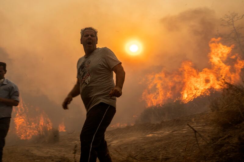 A local reacts as flames burn trees in the village of Gennadi on the Aegean Sea island of Rhodes. Photograph: Petros Giannakouris/AP