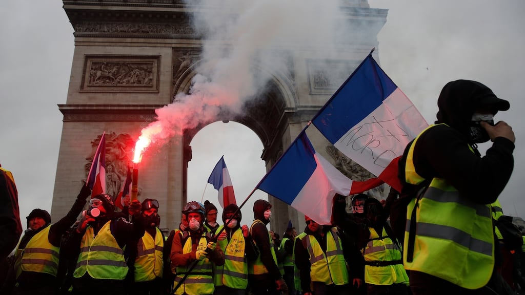 Protesters wearing yellow vests wave flares and French flags near the Arc de Triomphe during a demonstration over high fuel prices on the Champs Elysee, Paris, in December 2018. Photograph: Yoan Valat/EPA