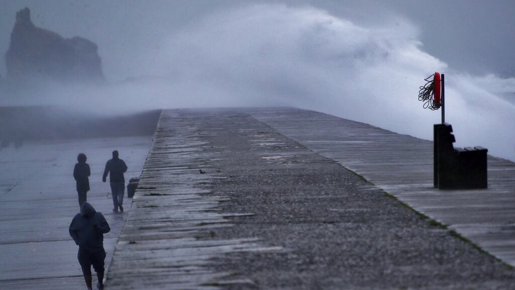 Walkers in Howth, Dublin,  as waves crash over the harbour wall on Tuesday morning. Photograph:  Colin Keegan/Collins