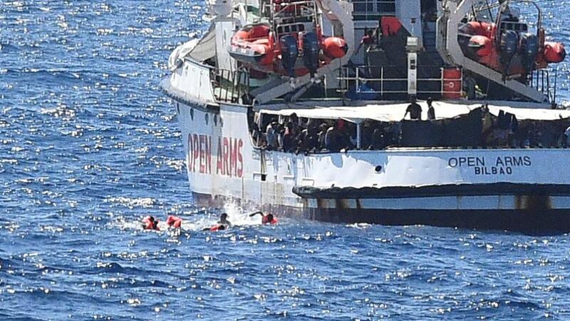 Migrants swim after jumping off the Spanish rescue ship Open Arms. Photograph: Guglielmo Mangiapane/Reuters