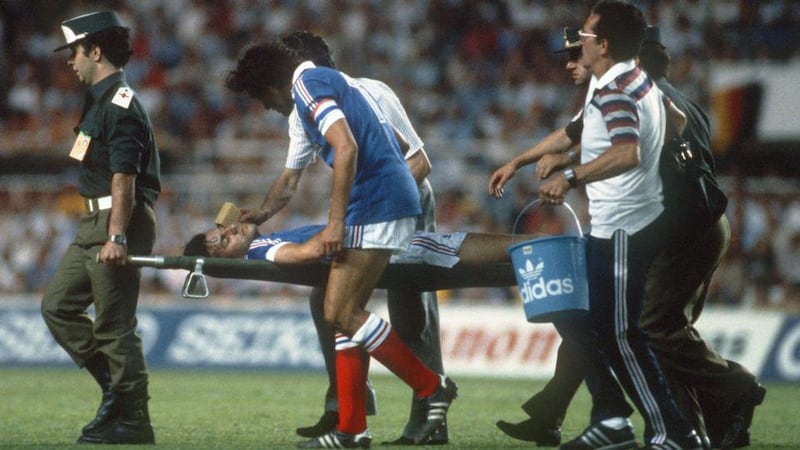 French captain Michel Platini comforts the stricken Patrick Battison as he is being taken off the firld by stretcher in Seville. Photograph: AFP