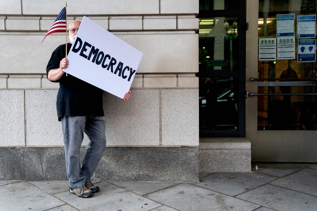 A demonstrator holds a sign reading Democracy outside the United States District Court House on the first day of jury selection for former White House Chief Strategist Steve Bannon, in Washington, DC, on July 18, 2022. Photograph: Stefani Reynolds /AFP/Getty