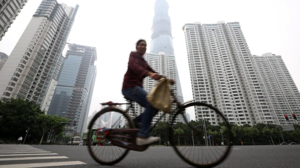 A woman rides a bicycle past the Shanghai Tower, under construction in the Lujiazui district of Shanghai. Chinese president Xi Jinping has promised to reform the Chinese economy to encourage more domestic consumption and to reduce its reliance on exports. Photograph: Tomohiro Ohsumi/Bloomberg