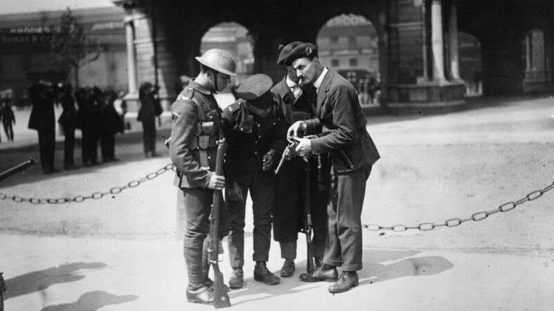 British soldiers watch a member of the Black and Tans, an armed auxiliary force of the Royal Irish Constabulary, reload his .45 revolver, after the burning of the Custom House in Dublin (headquarters of the British Civil Service in Ireland). Photograph: Walshe/Getty Images